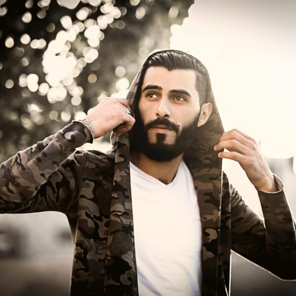 Portrait of a stylish man wearing a camouflage hoodie outdoors, captured in warm sunlight.